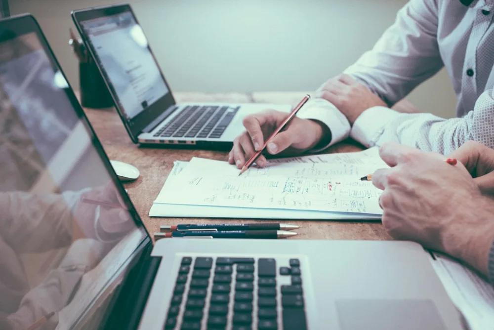 Profissionais analisando documentos em uma mesa de trabalho.